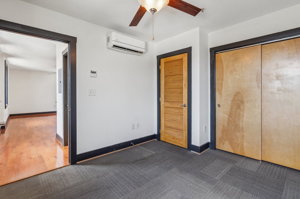 an empty room with two doors and a ceiling fan