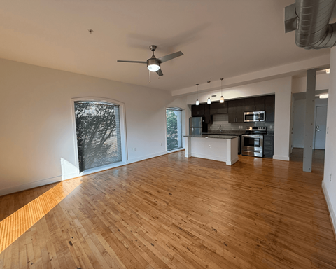 A spacious room with wooden flooring and a ceiling fan.