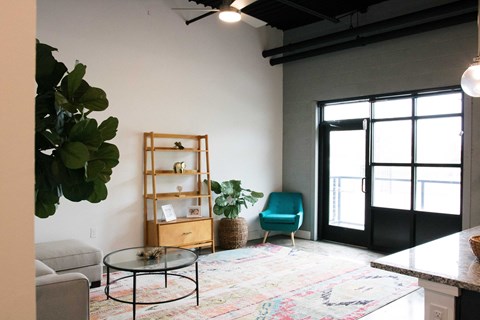 A living room with a glass table and a blue chair.