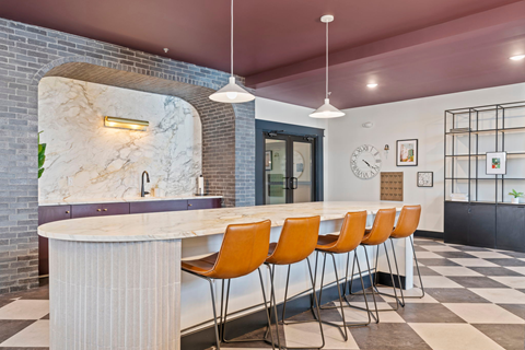 a kitchen with a marble counter top and orange chairs