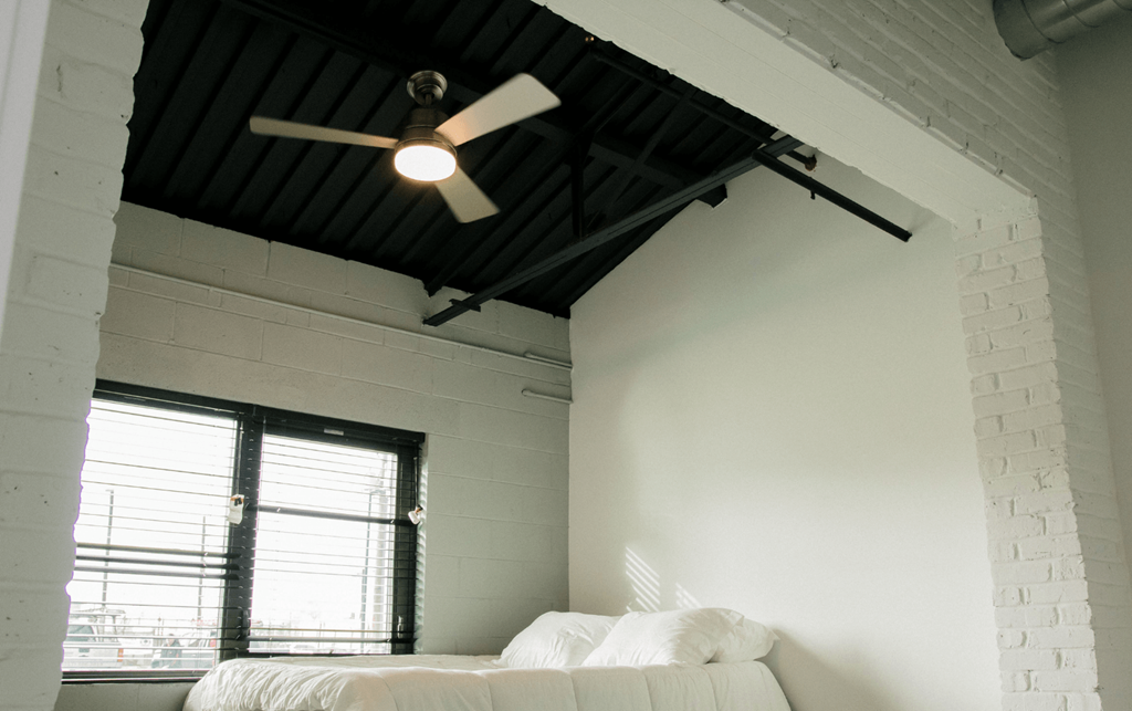 a bedroom with a white bed and a ceiling fan