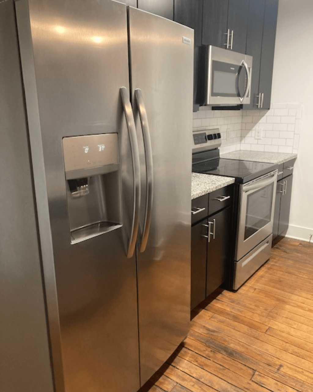 a stainless steel refrigerator in a kitchen with a wooden floor