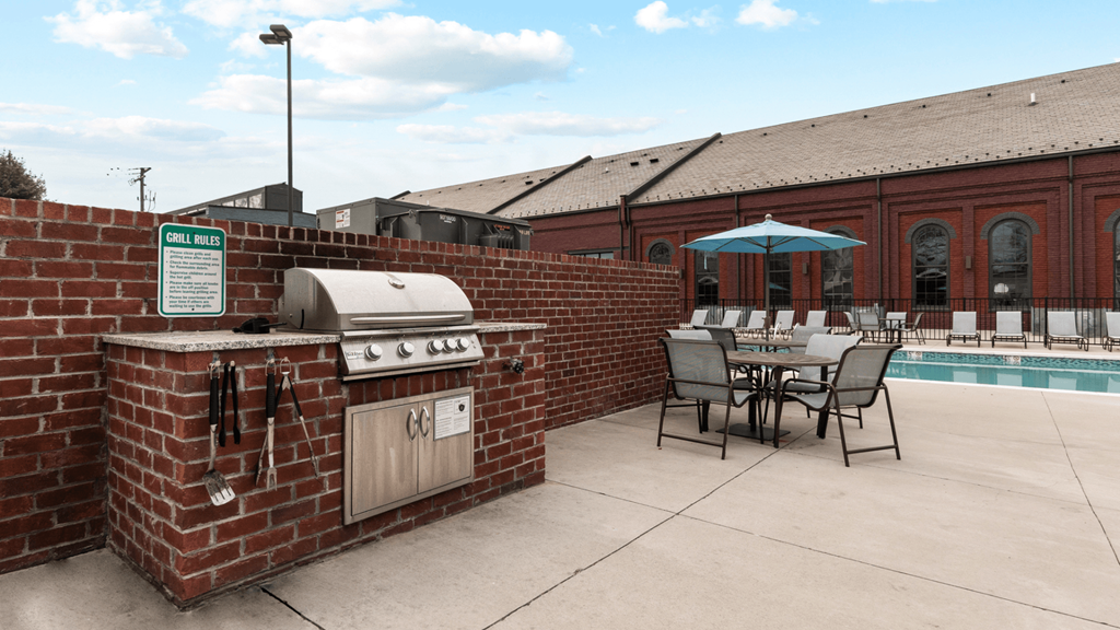 a patio with a barbecue grill next to a pool