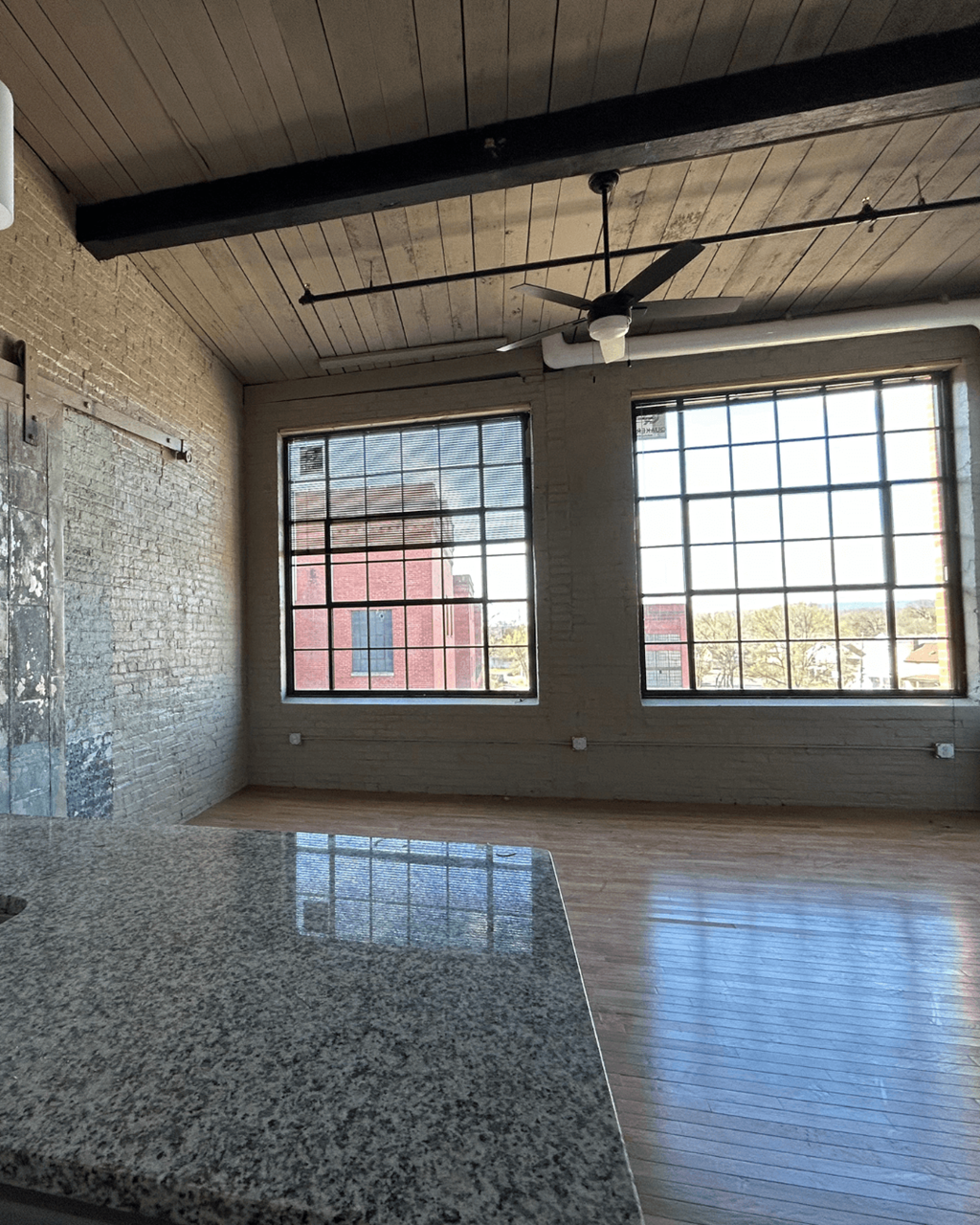 an empty room with two large windows and a tile floor