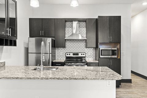 A modern kitchen with a granite countertop and stainless steel appliances.