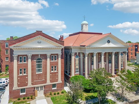 an aerial view of a brick building with columns and a bell tower