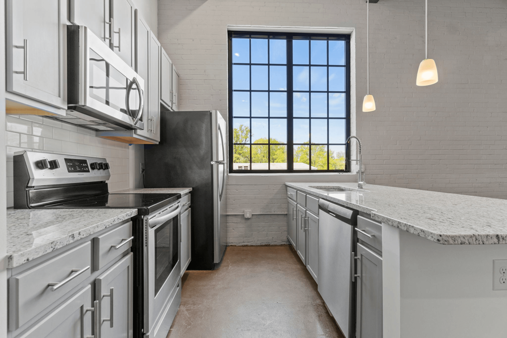 a large kitchen with white cabinets and a window