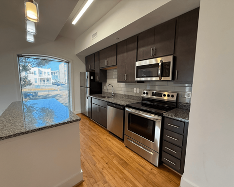 A modern kitchen with stainless steel appliances and wooden floors.