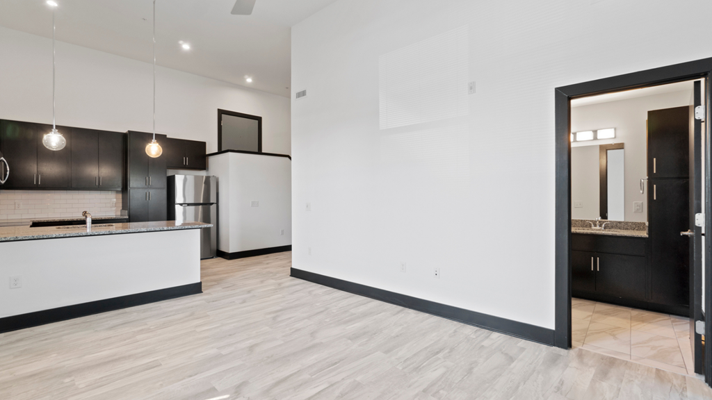 an open kitchen and living room with white walls and wood flooring