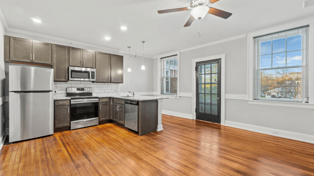 an empty kitchen with stainless steel appliances and wood floors