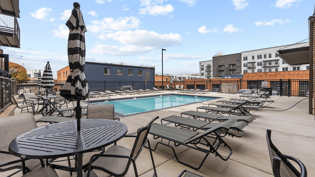 an outdoor pool with tables and chairs and a poolside umbrella