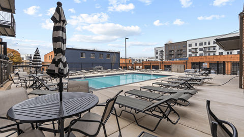 an outdoor pool with tables and chairs and a poolside umbrella