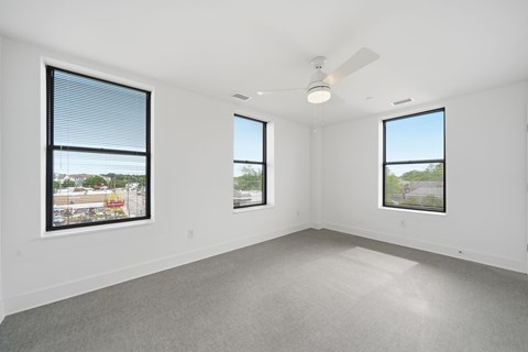 A spacious room with three windows and a ceiling fan.