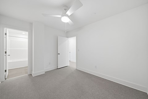 A room with a ceiling fan and carpeted floor.