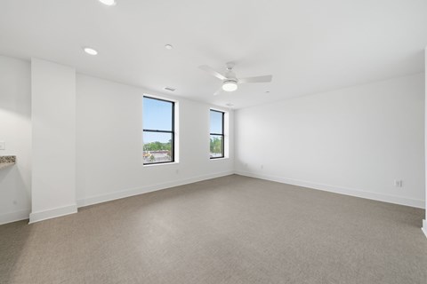A large empty room with a window and a ceiling fan.