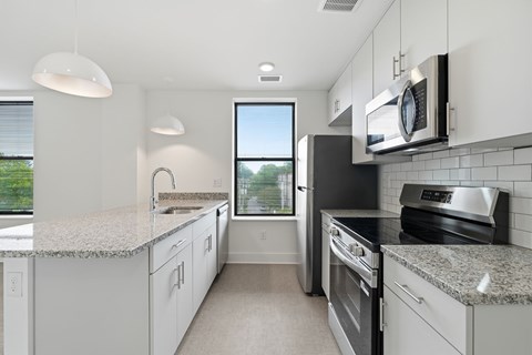 A kitchen with white cabinets and granite countertops.