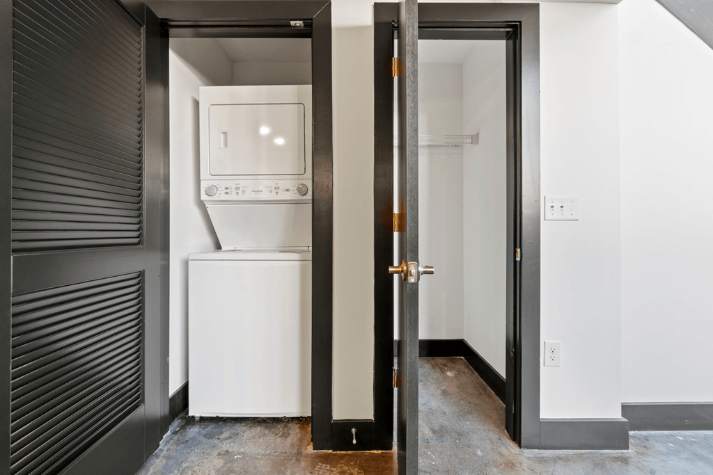 a white room with a white washer and dryer and a black door