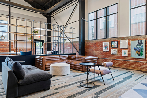 a living room with leather furniture and exposed brick walls