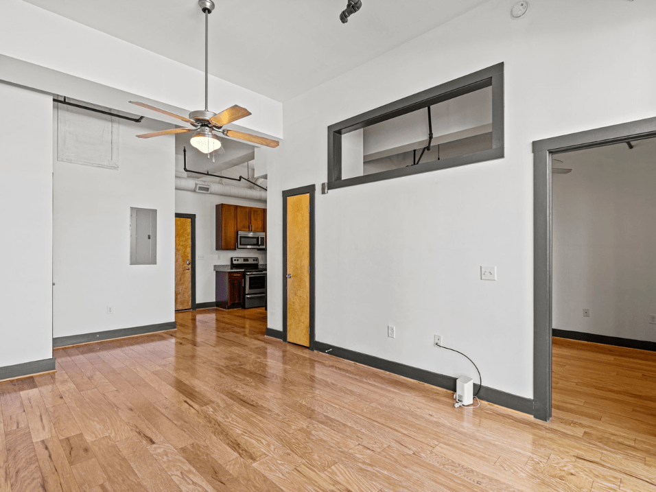 an empty living room with a wood floor and a ceiling fan