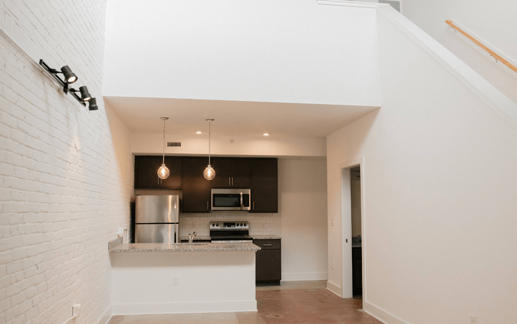 a white kitchen with a large island and a white brick wall