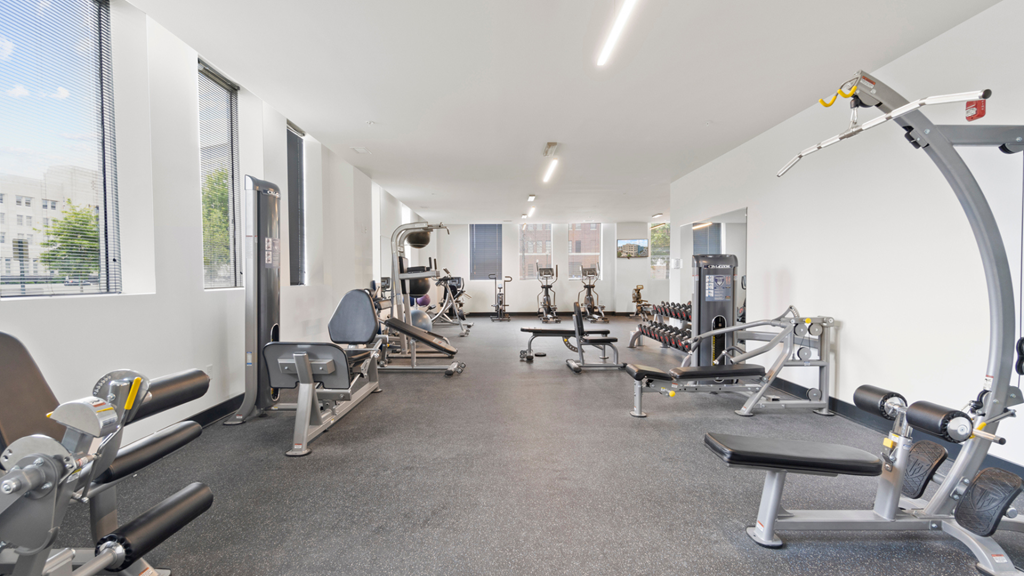 a gym with cardio equipment and weights on the floor