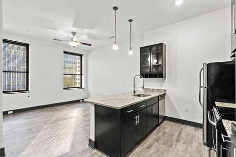 A kitchen with black cabinets and a marble countertop.