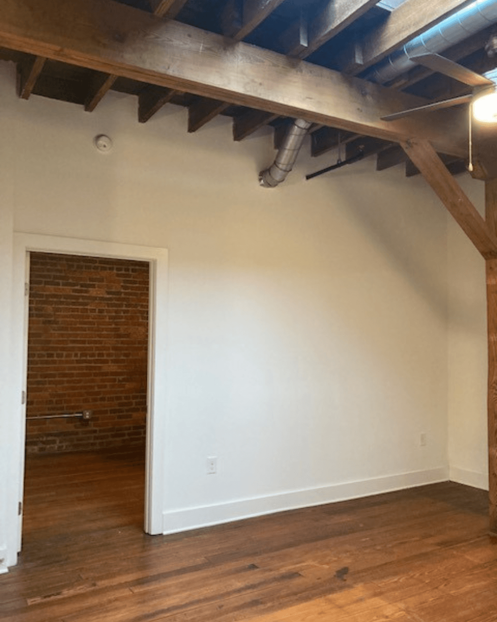 an empty room with a white wall and wooden floors