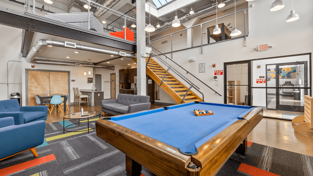 a game room with a pool table and a staircase