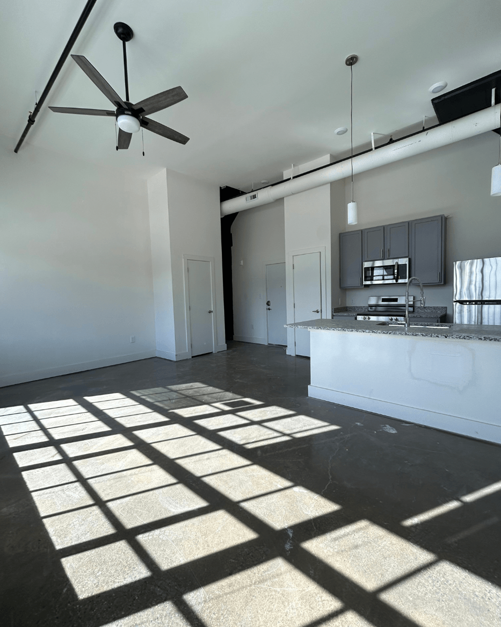 an empty room with a kitchen and a ceiling fan