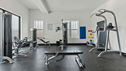 a gym with weights and other equipment in a room with windows