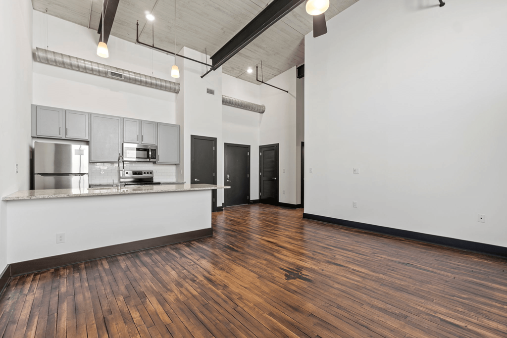 the interior of a studio apartment with a kitchen and hard wood floors