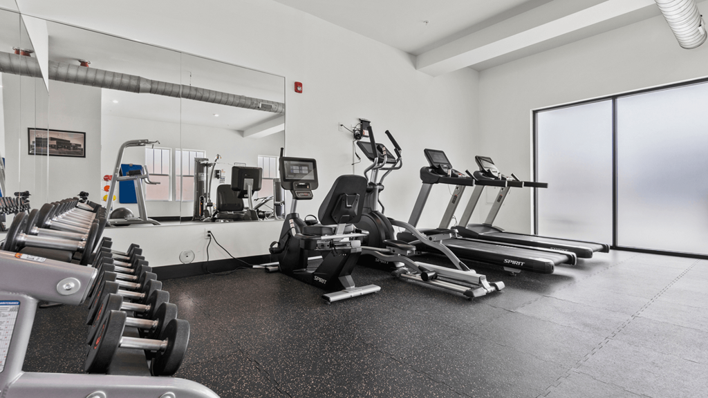 a gym with cardio machines and weights on the floor