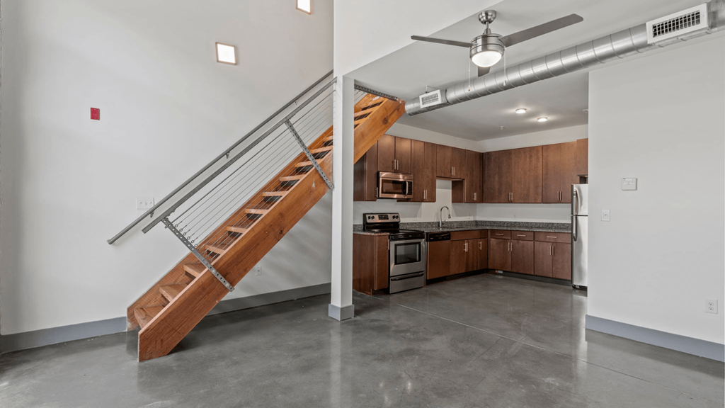 an empty kitchen with a staircase and a stainless steel stove and refrigerator