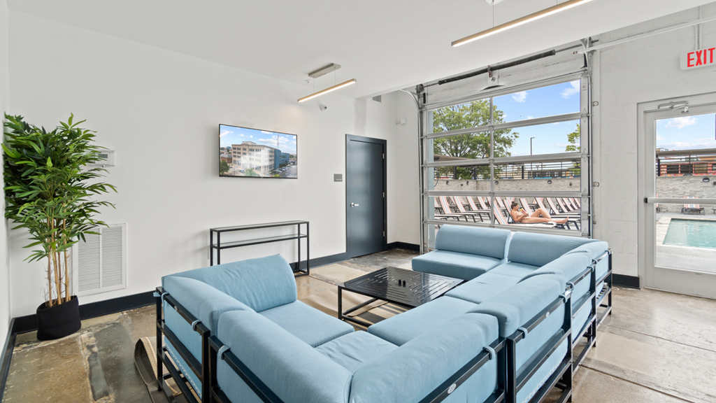 a living room with two blue couches and a glass coffee table and a window