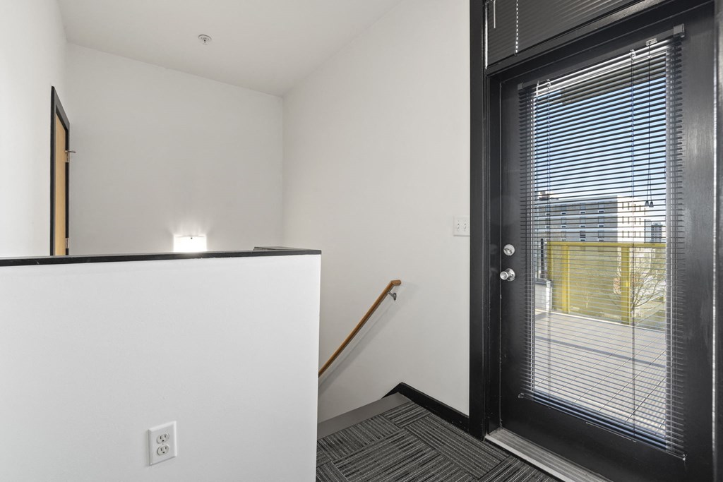 the entryway of a house with a black door and white walls and a staircase