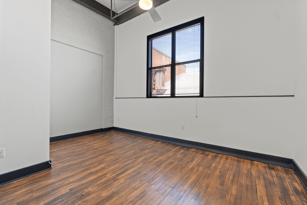 an empty room with white walls and wood floors and a window