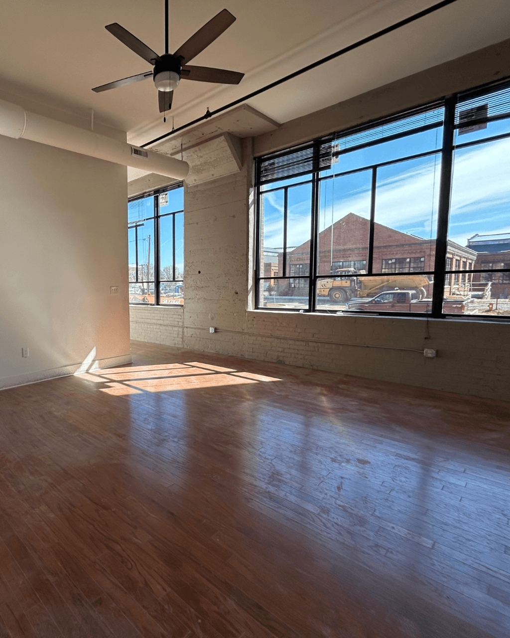 an empty living room with wood floors and large windows