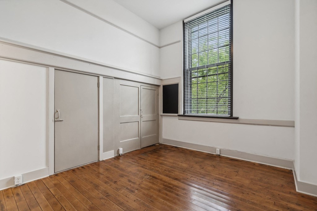 an empty room with wood floors and white walls and a window