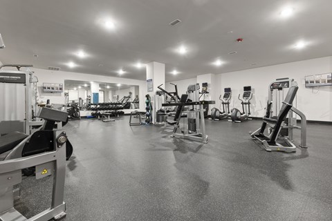 A black and white image of a gym with various exercise equipment.