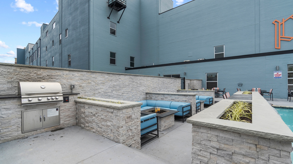 a patio with a grill and seating area and a pool