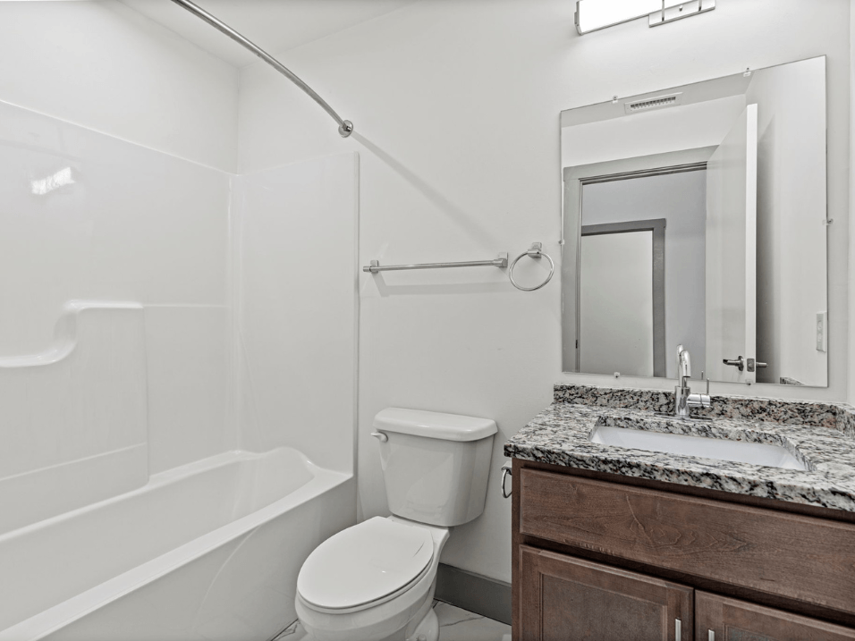 a bathroom with a toilet sink and shower and a mirror