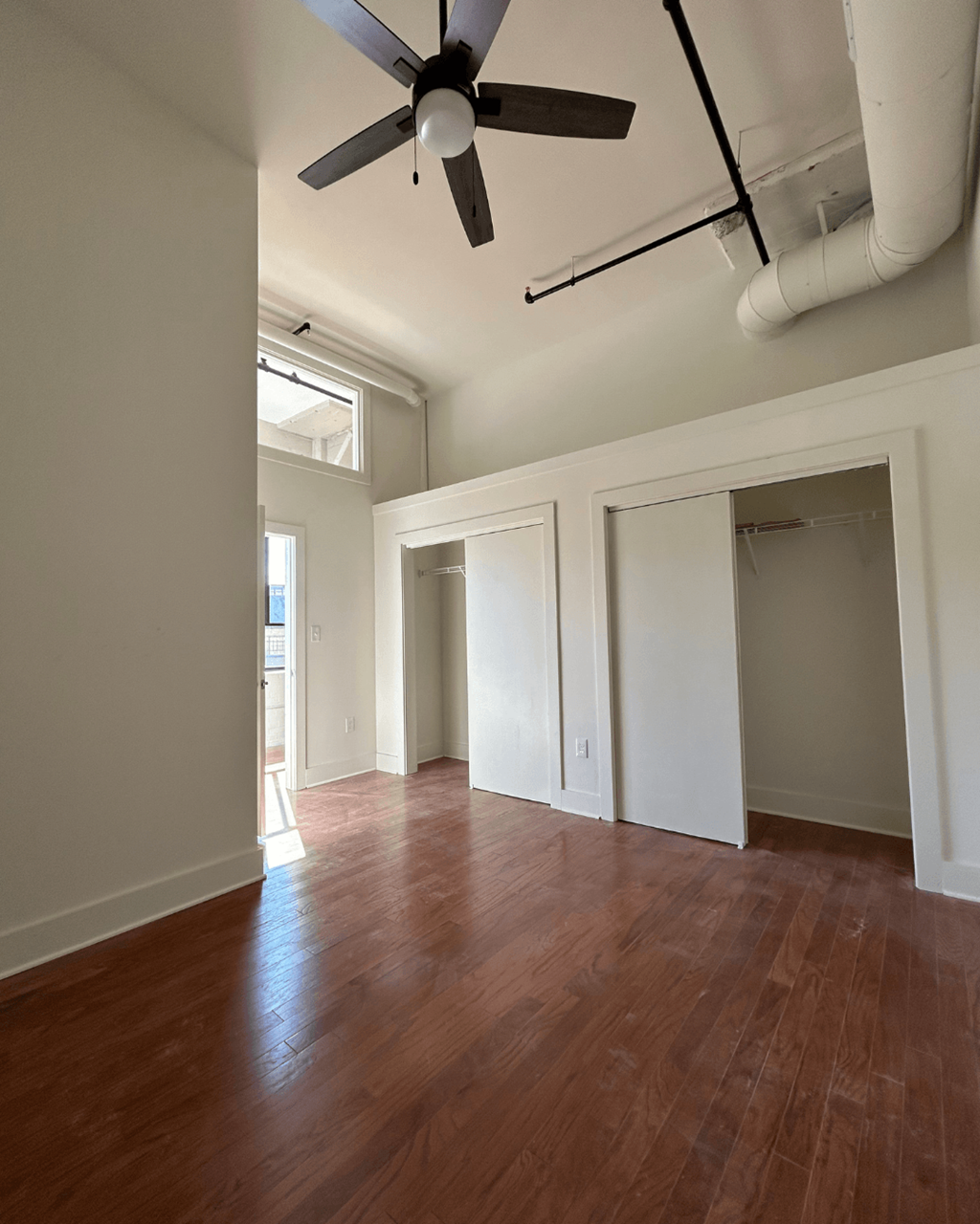 an empty living room with wood floors and a ceiling fan