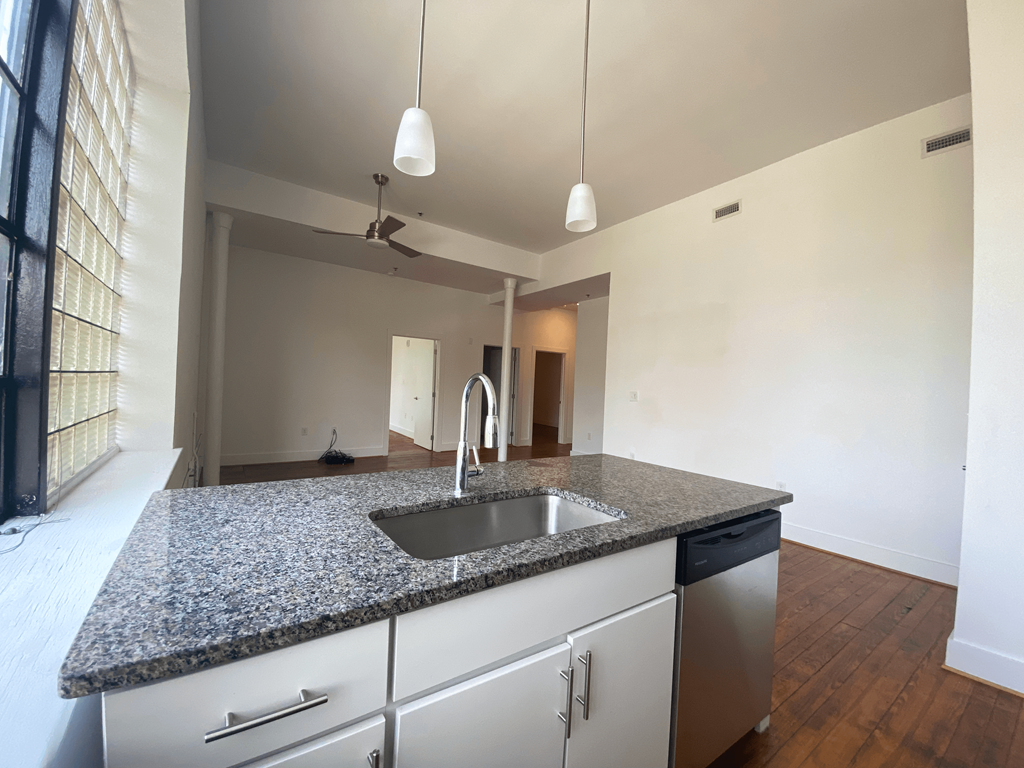 an empty kitchen with granite counter tops and a sink