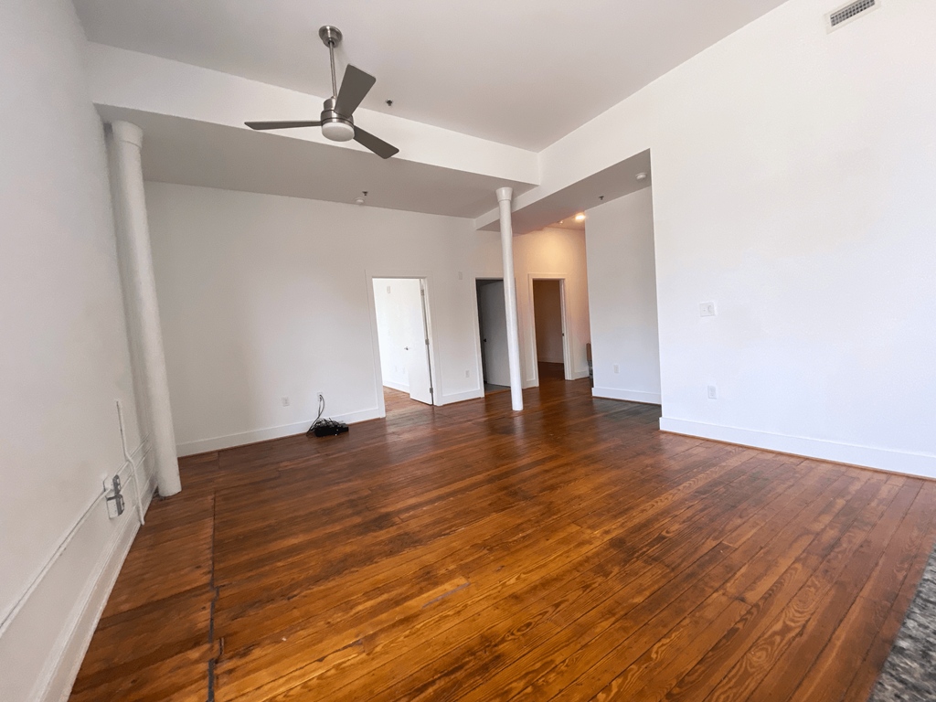 an empty living room with wood floors and white walls