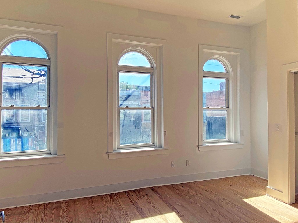 a living room with three windows and a wooden floor