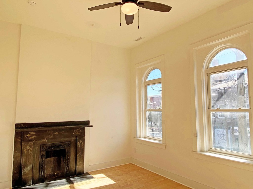 an empty living room with a fireplace and a ceiling fan