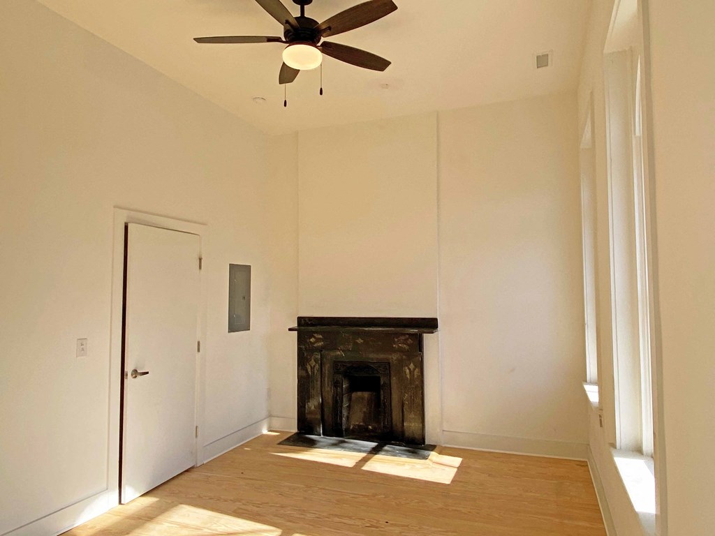 an empty living room with a fireplace and a ceiling fan