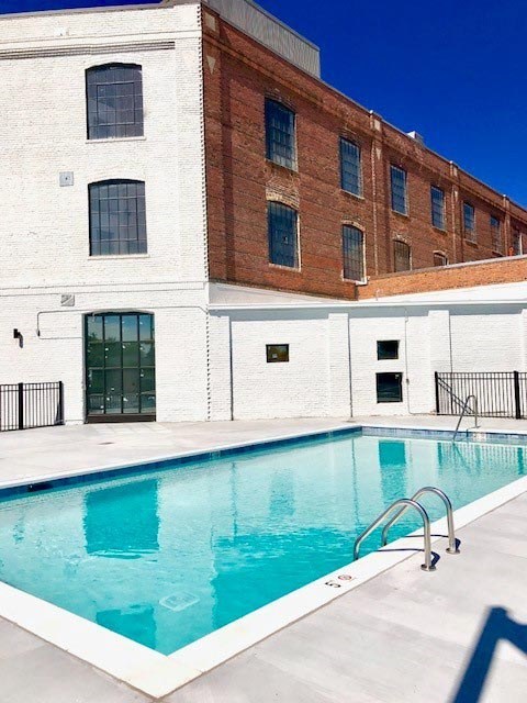 A swimming pool in front of a white and brick building.