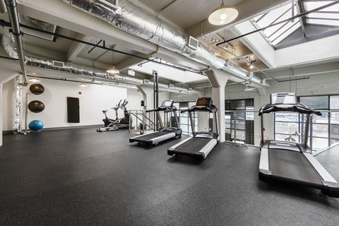 A gym with treadmills, exercise balls, and weights.