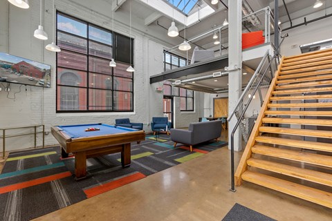 A room with a pool table and a staircase.